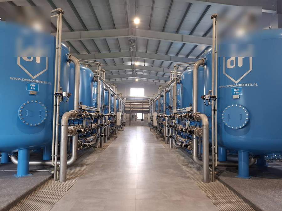 Indoor multimedia filter installation with rows of blue epoxy-coated pressure vessels and stainless steel pipework manifold