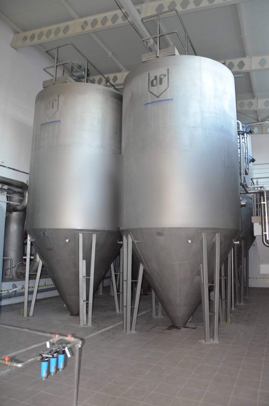 Pair of vertical 316L stainless steel pressure filter vessels with 60-degree conical hopper discharge bottoms, installed indoors