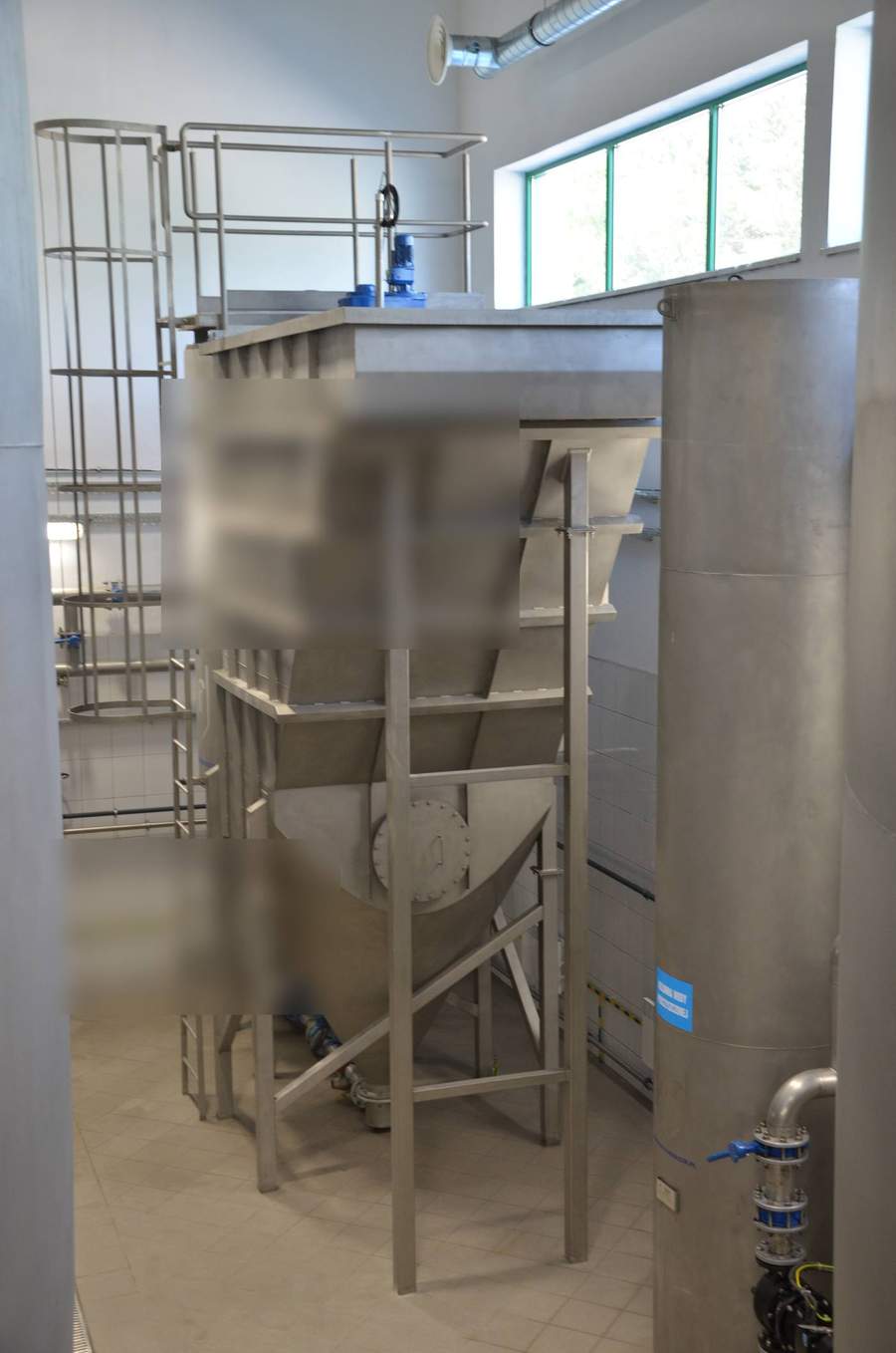 Overhead view of stainless steel conical filter vessel and rectangular lamella clarifier installation in a water treatment facility